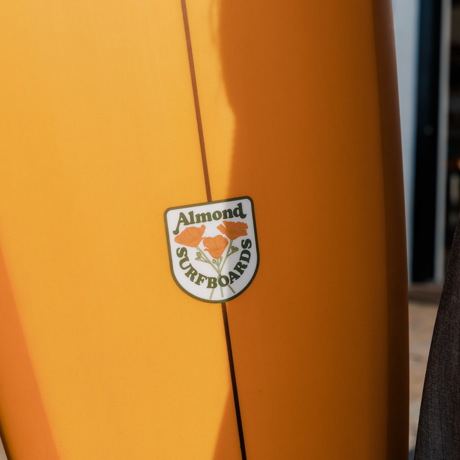 Close-up of an orange surfboard with a visible brand logo.